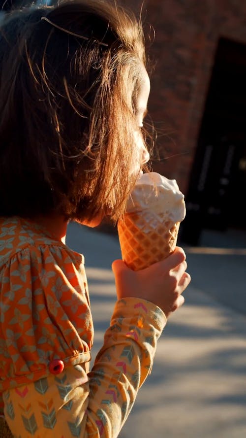 Girl Wearing an Orange Dress While Eating Ice Cream