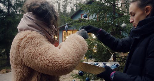 Two Woman Decorating a Fir Tree with Christmas Ornaments and Balls