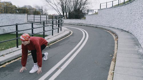 A Woman Warming Up then Running on a Track and Field