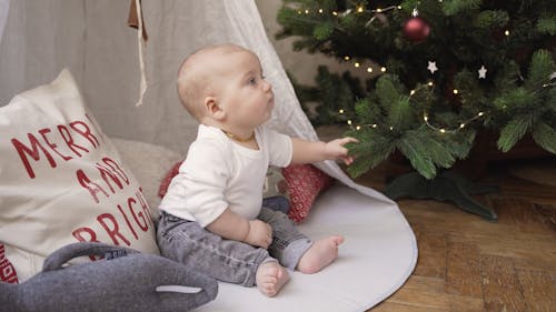 Baby Playing on the Floor Beside Christmas Tree