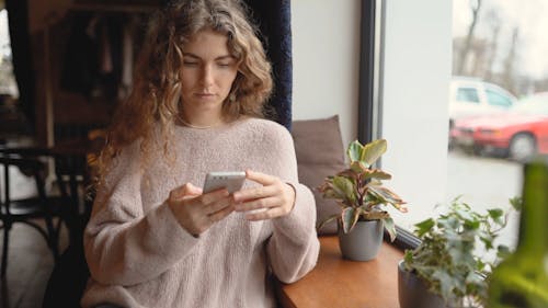 Young Woman Sitting by Window Making Phone Call