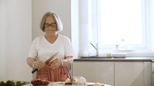 Elderly Woman Cutting Red Bell Peppers