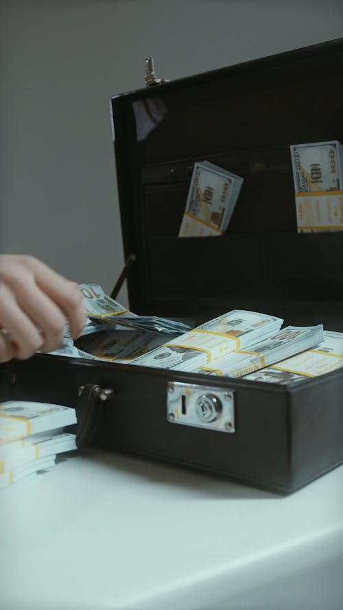 Hands Putting Dollar Bills Stacks in Briefcase