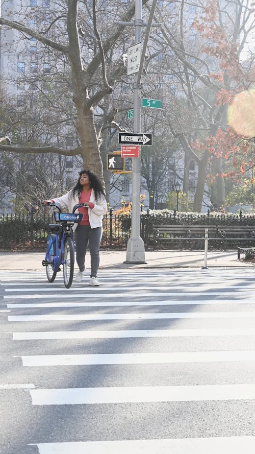 Woman Crossing the Street with a Bike 