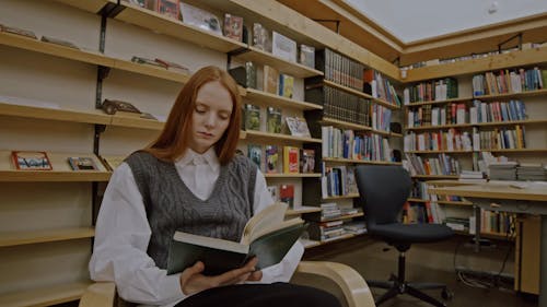 Young Female Student Reading Book in Library 