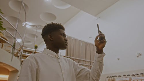 A Man Recording a Video with his Cellphone in a Library