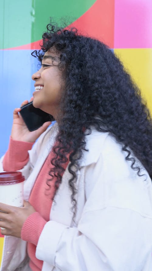 Woman Talking on the Phone While Holding a Cup