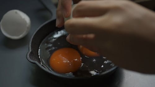 Crop Person Cracking Eggs on Frying Pan