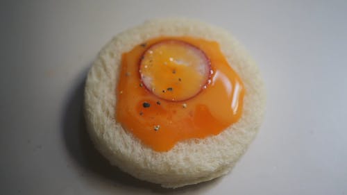Close Up View of Sprinkling Peppers on a Bread with Egg Yolk
