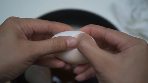 A Person Opening a Boiled Egg