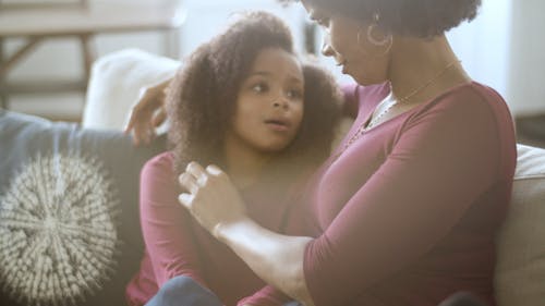 Mother And Daughter Sitting On A Sofa