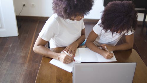 Woman And Little Girl Writing On A Notebook