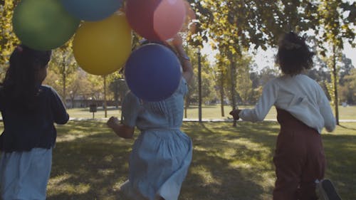 Three Girls Running on the Park Holding Balloons