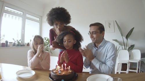 A Family Clapping in front of a Birthday Cake