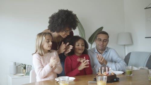 A Family Singing and Clapping in front of a Birthday Cake