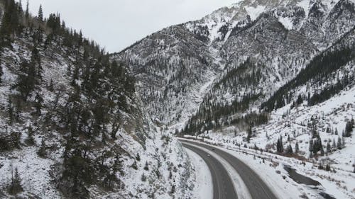Drone Footage of the Roadway in the Middle of Snow Covered Mountains