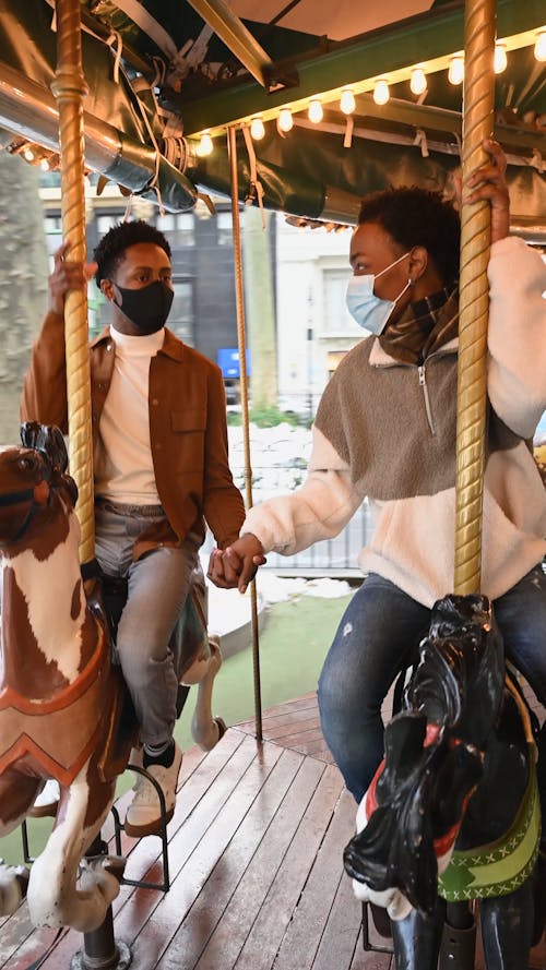 People Holding Hands while Riding a Carousel