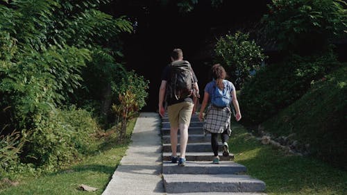 Man and Woman Wearing Backpacks Walking Up-stairs