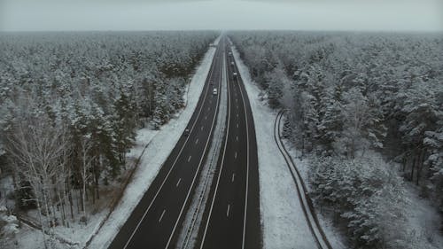 Drone Footage of a Road in the Middle of a Snowy Forest