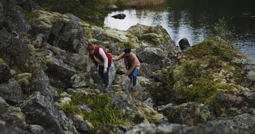 Couple Climbing Rocks In The Lake Shore