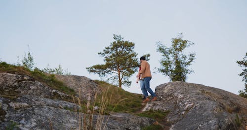 A Couple Stepping Down a Mountain Cliff