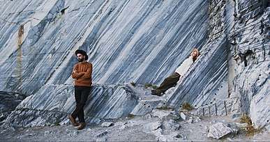 man and woman posing for the camera at ruskeala marble wall