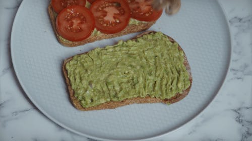 Person Placing Sliced Mushroom on the Avocado Toast