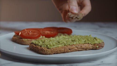 A Person Putting Mushroom on Top of Avocado Toast