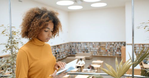 A Woman Reading A Book Inside The Library