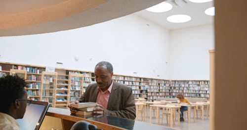 A Man Borrowing Books From The Library
