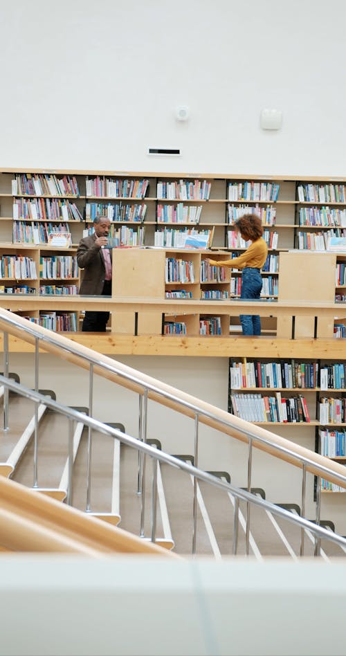 A Man Walking Inside a Library