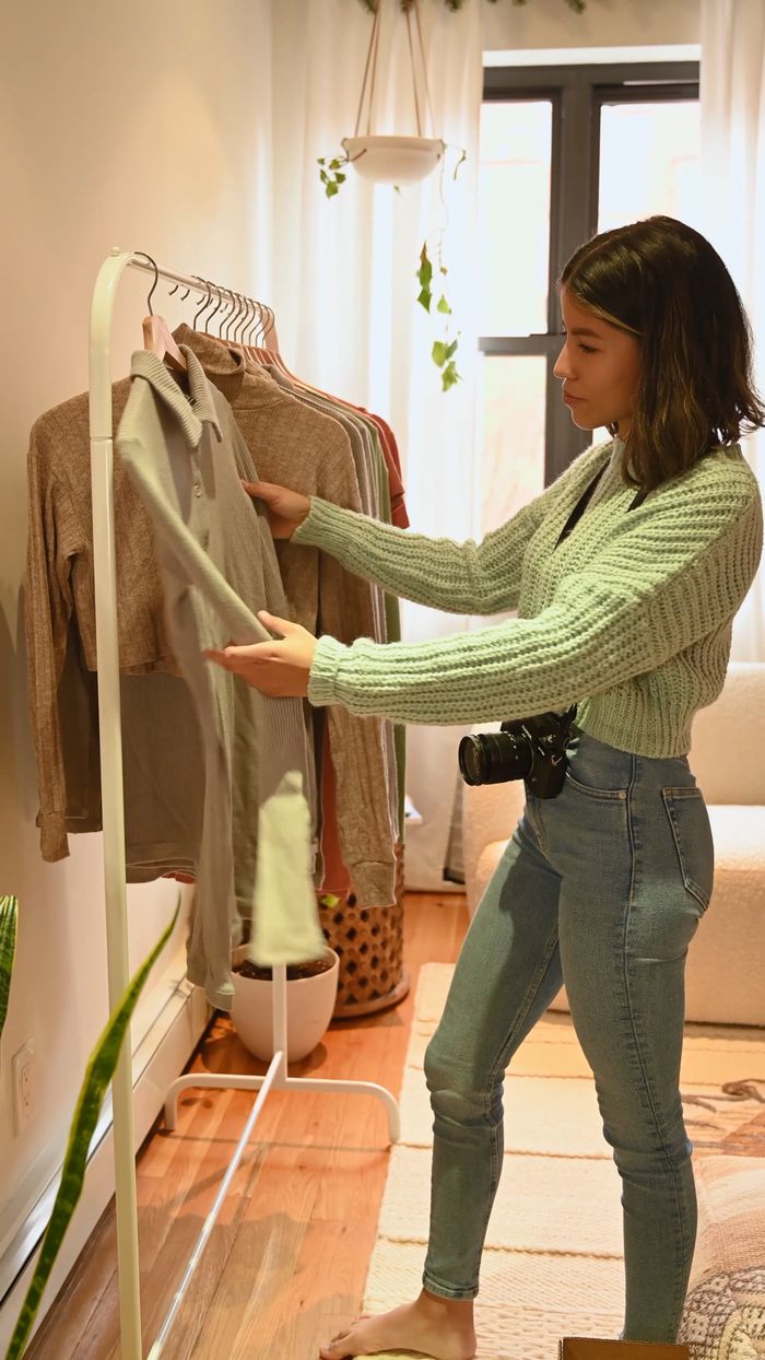 Woman in a sage knit browsing a clothing rack
