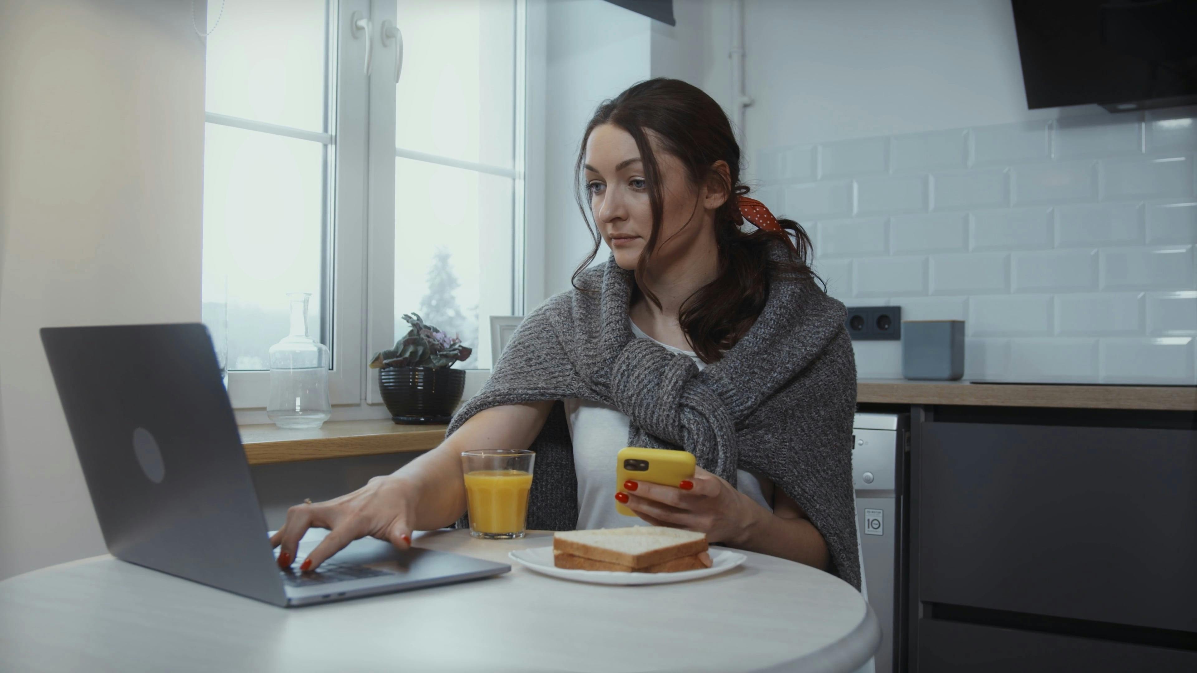 Woman Using Her Phone While Using a Laptop · Free Stock Video