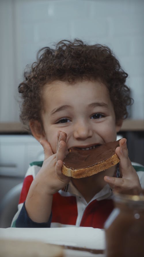 A Boy Eating Bread with Chocolate Spread