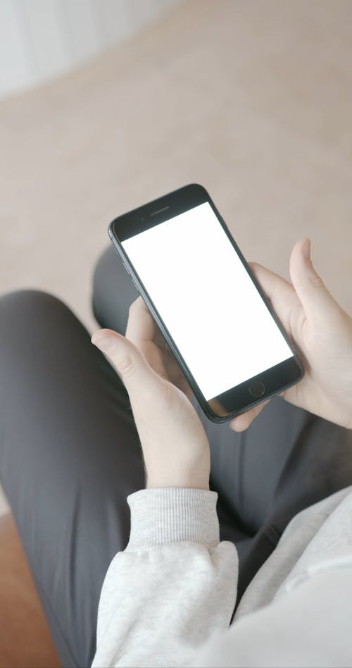 Person Holding a Mobile Phone with White Screen
