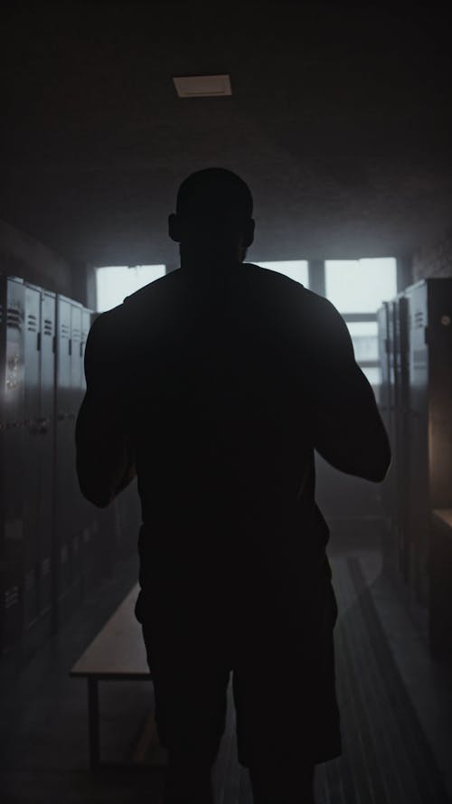 A Man Removing His Shirt and Putting it in the Locker