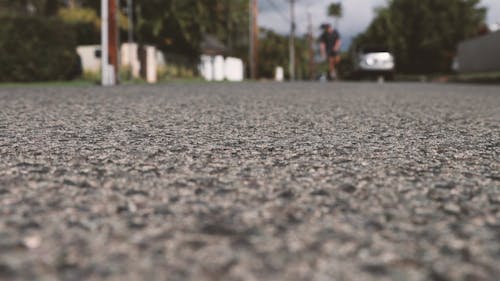 Close Up View of Asphalt Road with a Man Playing Skateboard