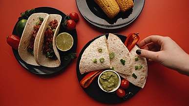 a woman getting a quesadilla and a corn from the plates