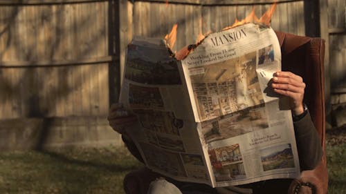A Person Reading a Burning News Paper