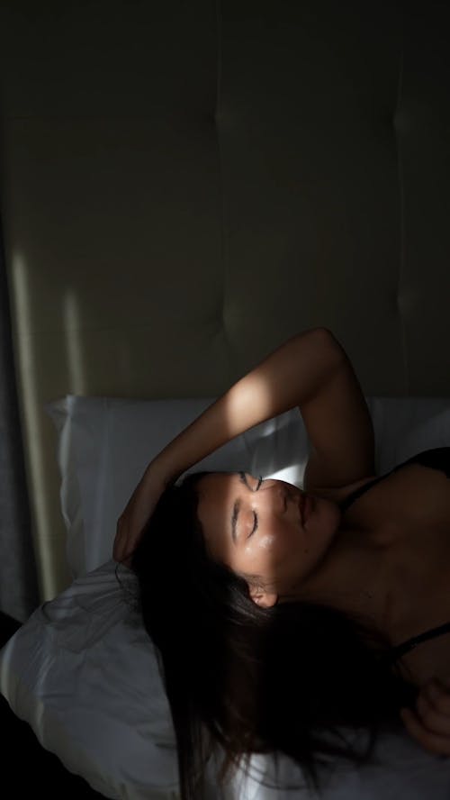 A Woman Lying Down on a Bed while Posing