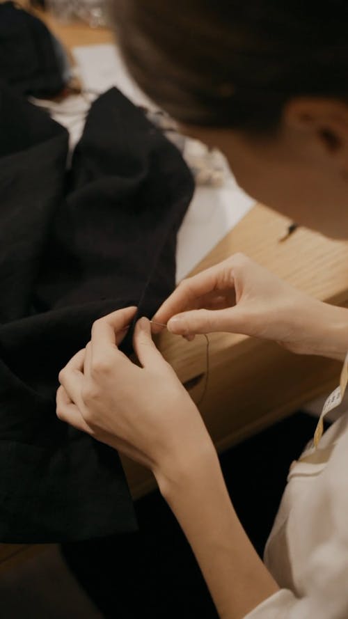 Woman Sewing Buttons on Coat