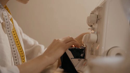 Side View of a Woman Stitching a Fabric with a Sewing Machine