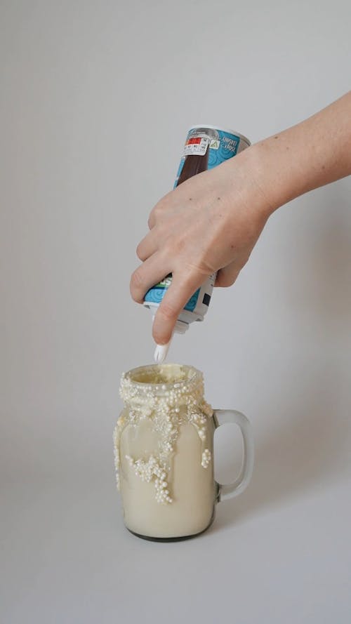 A Person Putting Whipped Cream on the Milk Shake
