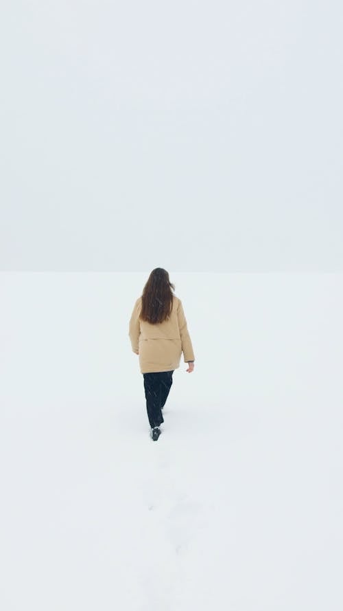 Woman Walking on a Snow Covered Road