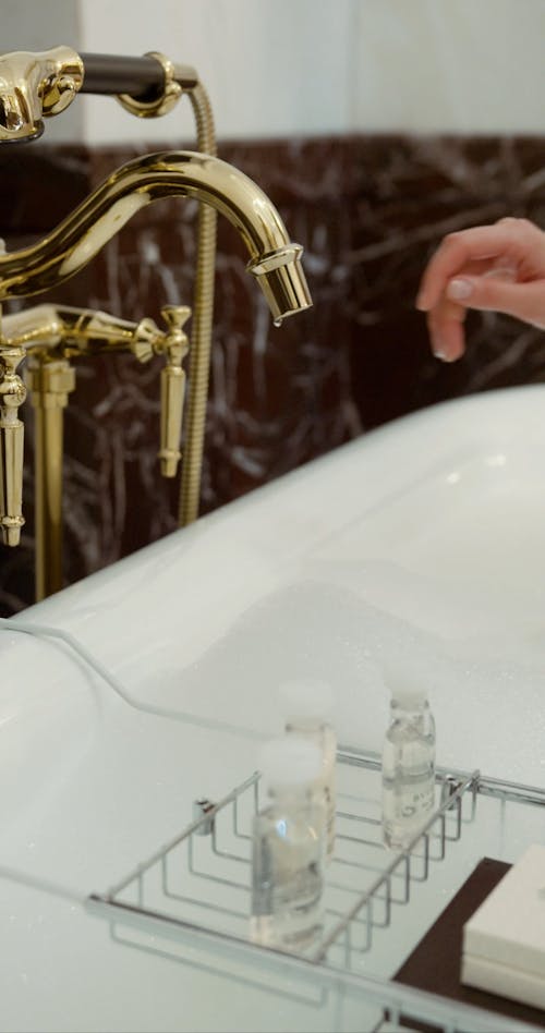 Woman Opening Faucet of Luxurious Bathtub