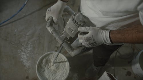A Man Using Hand Held Construction Mixer