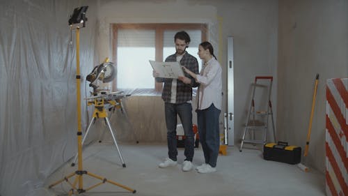 Man and Woman Talking about Home Renovation with Blueprint in Hand