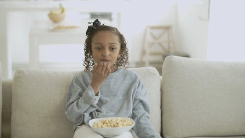 A Kid Eating Popcorn while Watching TV