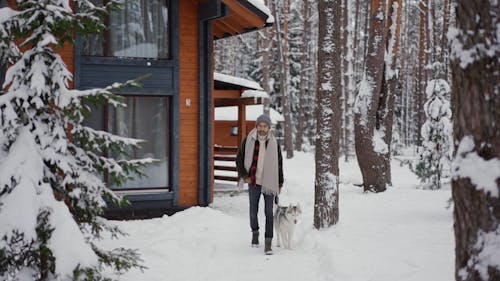 A Man Walking with His Dog on the Snow