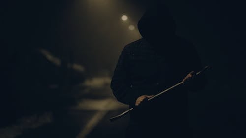 Man Standing in a Dark Alleyway Holding a Crowbar